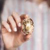 woman holding small easter egg covered in gold foil