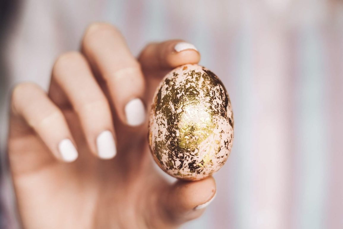 woman holding small easter egg covered in gold foil